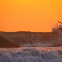 Surfer-vor-orangem-Himmel