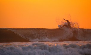 Surfer vor orangem Himmel Wandbild